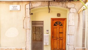 A building entrance with a stone archway, a wooden door marked with the number 23, and a sign reading "CARRER DE LA CIVADERIA". - Unik Vacation Dames i Vells (Tarragona)