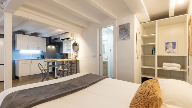 Ett modernt hotellrum med en säng, ett skrivbord och ett litet kök.