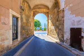 A narrow street with stone walls and an archway leading to a view of the sea. - Unik Vacation En Granada (Tarragona)