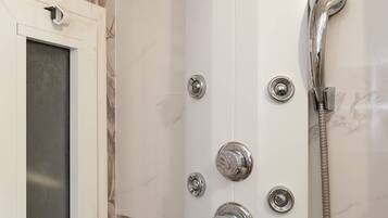 A shower enclosure with a handheld showerhead, a wall-mounted faucet, and a handheld shower hose.