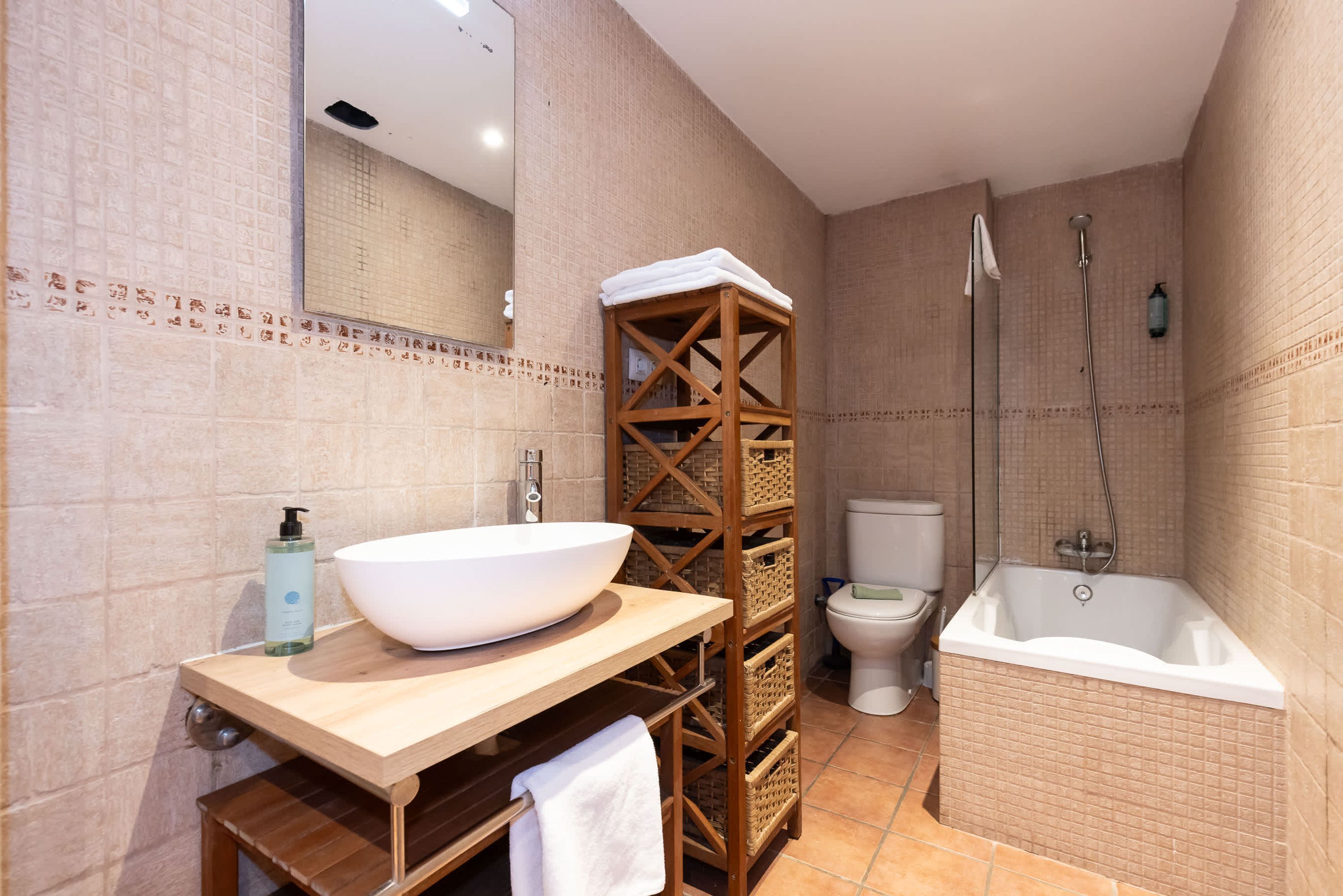 Une salle de bain avec un grand lavabo blanc, un meuble-lavabo en bois, des toilettes et une baignoire.