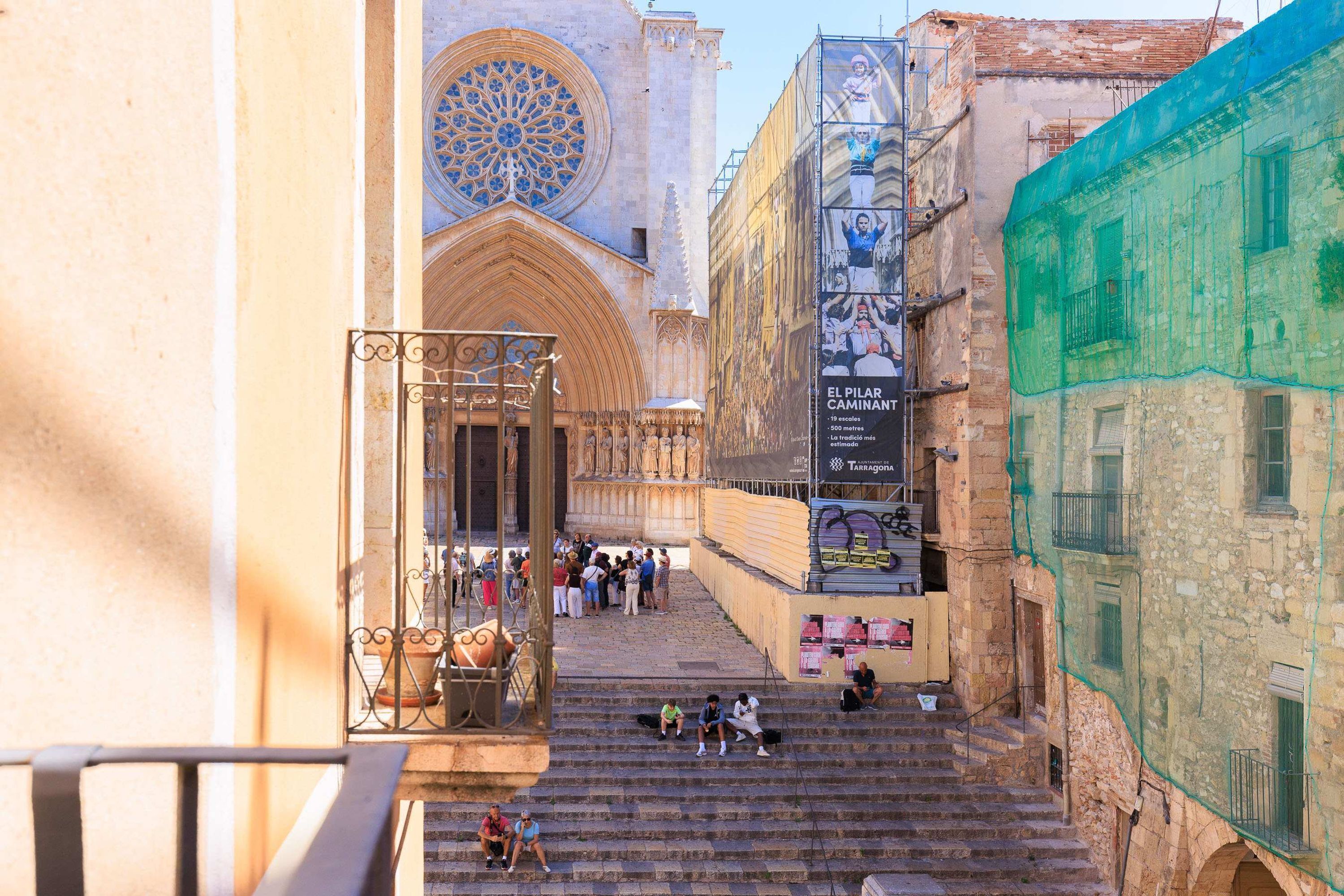 Un escalier menant à un bâtiment doté d’une grande fenêtre circulaire et d’une arche gothique.