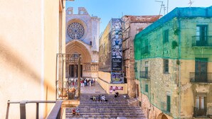 Un escalier menant à une cathédrale dotée d’une grande fenêtre circulaire, d’une bannière et d’un bâtiment agrémenté de balcons.