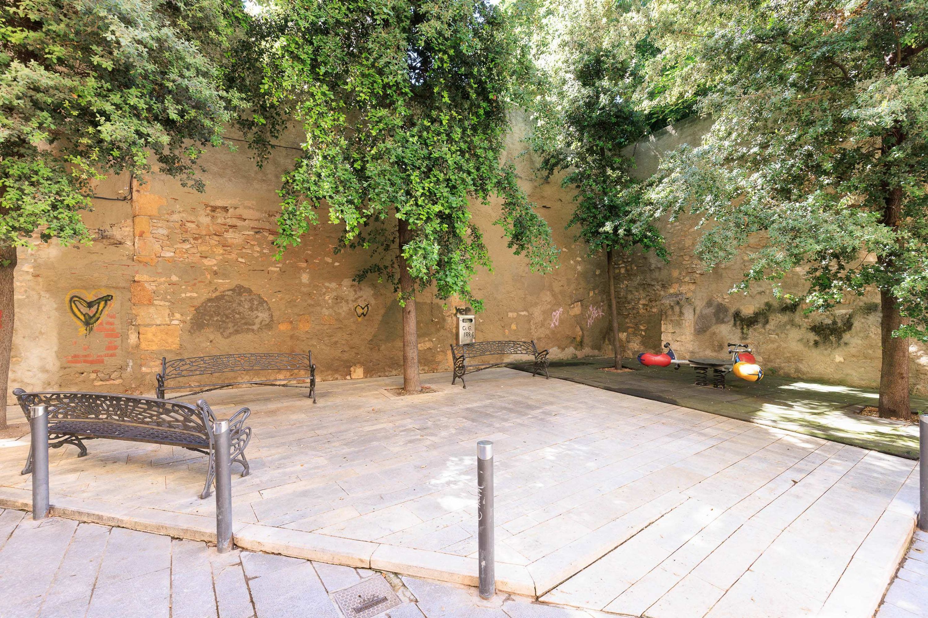 Area esterna con posti a sedere, uno scooter e un muro con graffiti.