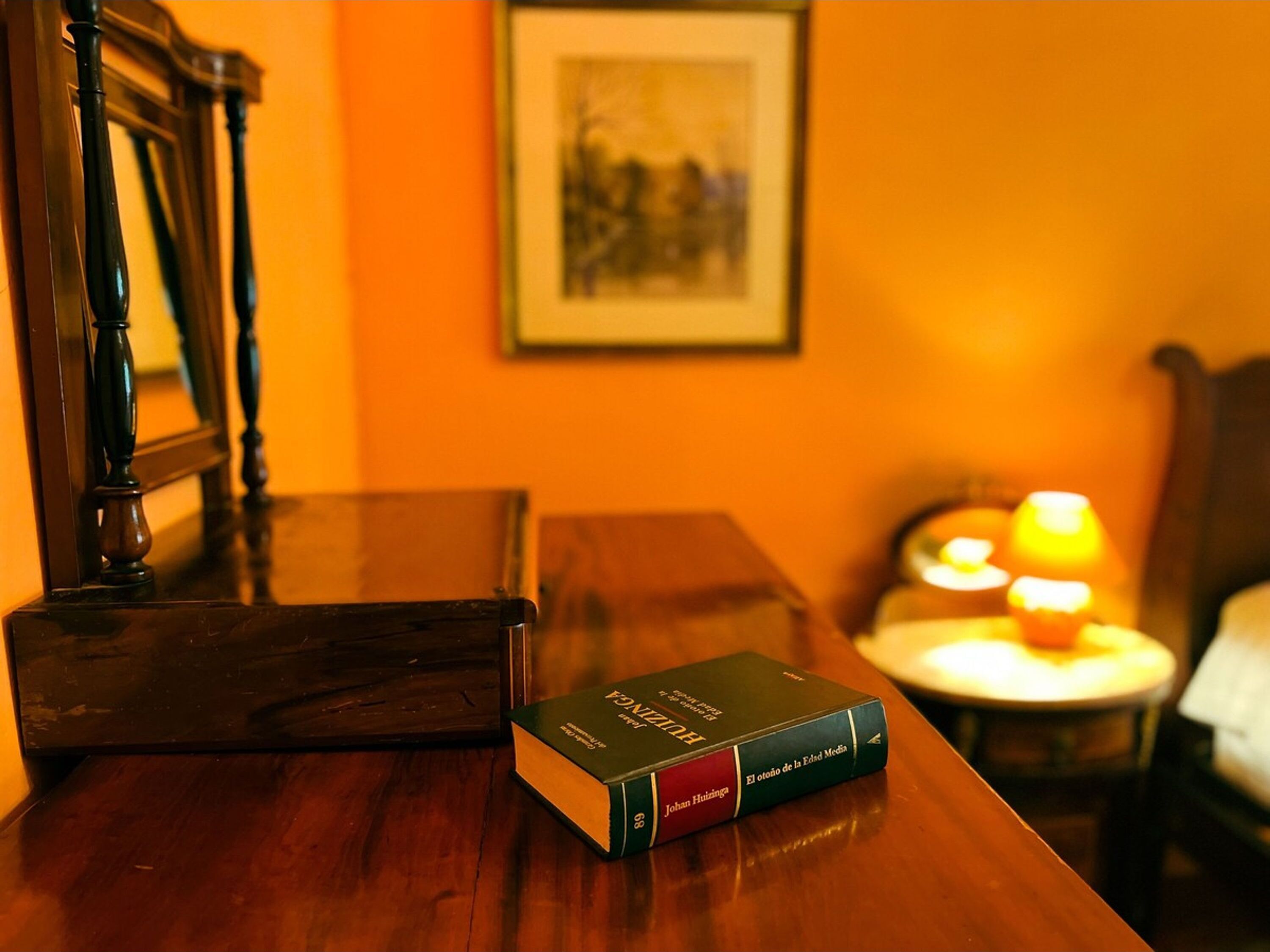A wooden table with a book titled "El origen de la Edm Media" by Johan Huizinga.