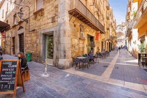 A narrow street with outdoor seating and stone buildings. - Unik Vacation Iconic (Tarragona)