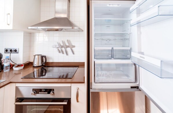 A modern kitchen with a built-in oven, a stainless steel range hood, and a Siemens refrigerator. - Unik Vacation Ferrers (Tarragona)
