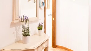 A hallway with a white wall, a mirror, a wooden door, and a tiled floor. - Unik Vacation Ferrers (Tarragona)