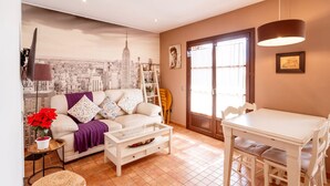 A living room with a sofa, coffee table, and a dining table. - Unik Vacation Ferrers (Tarragona)
