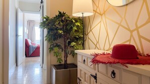 A hallway with a modern interior design, including a plant, a lamp, and a mirror on the wall. - Unik Vacation Marina (Tarragona)