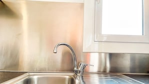 A stainless steel kitchen sink with a single faucet and a window above it. - Unik Vacation Attic in Tarragona (Tarragona)