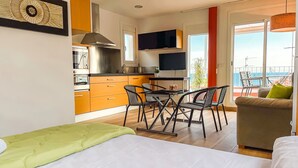 A modern kitchen with a dining area, a sofa, and a balcony with a view. - Unik Vacation Attic in Tarragona (Tarragona)