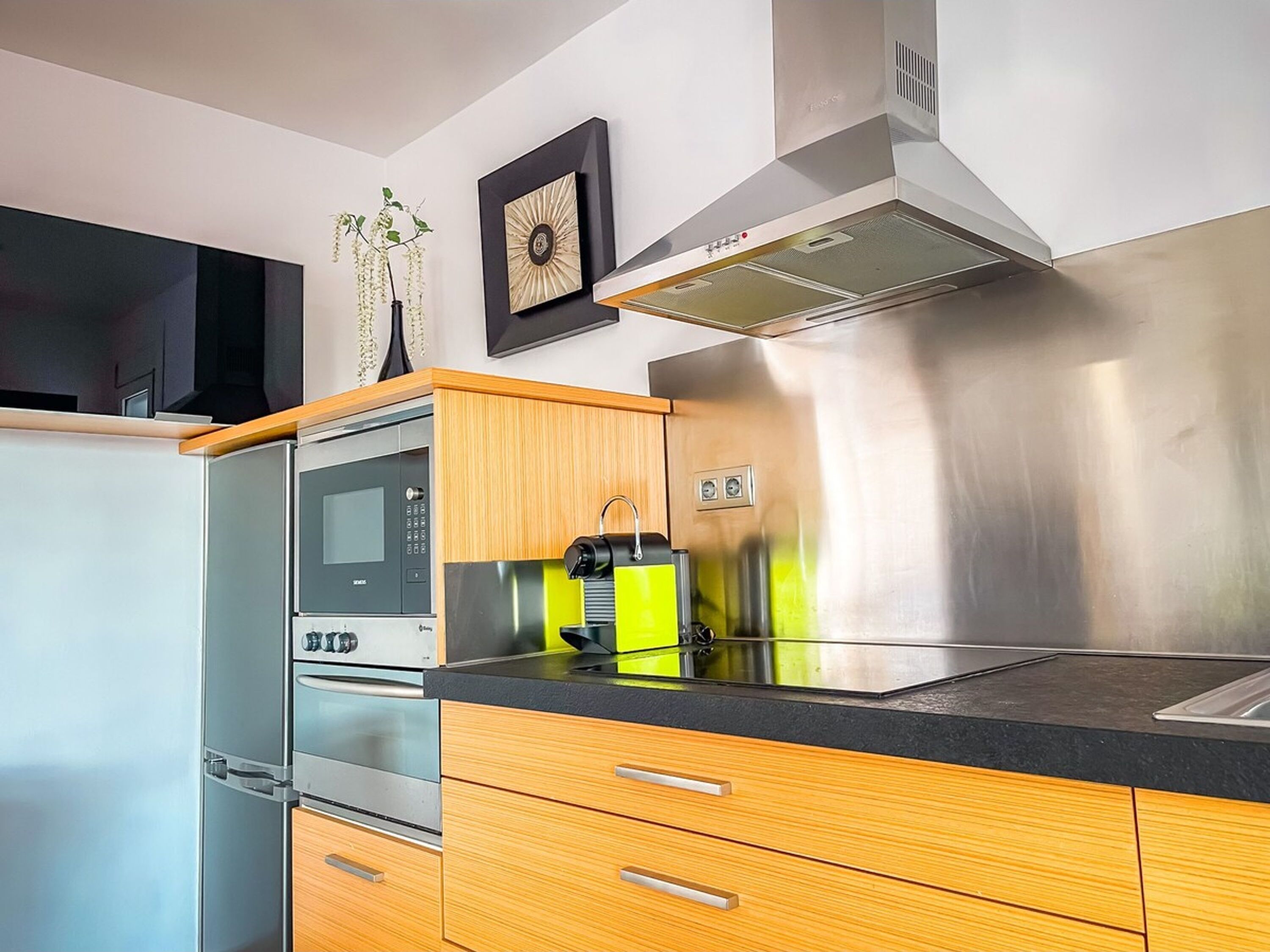 A modern kitchen with a built-in oven, microwave, and a stainless steel range hood.