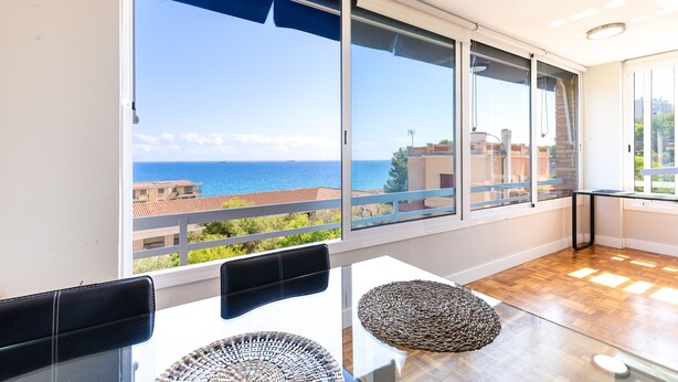 A balcony with a view of the sea, a glass table, and two black chairs. - Unik Vacation Via Augusta (Tarragona)