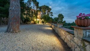 Une allée de gravier mène à un bâtiment aux murs de pierre, sur lequel se trouve un escalier.