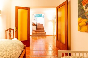 A hotel hallway with a bed, a staircase, and a painting on the wall.
