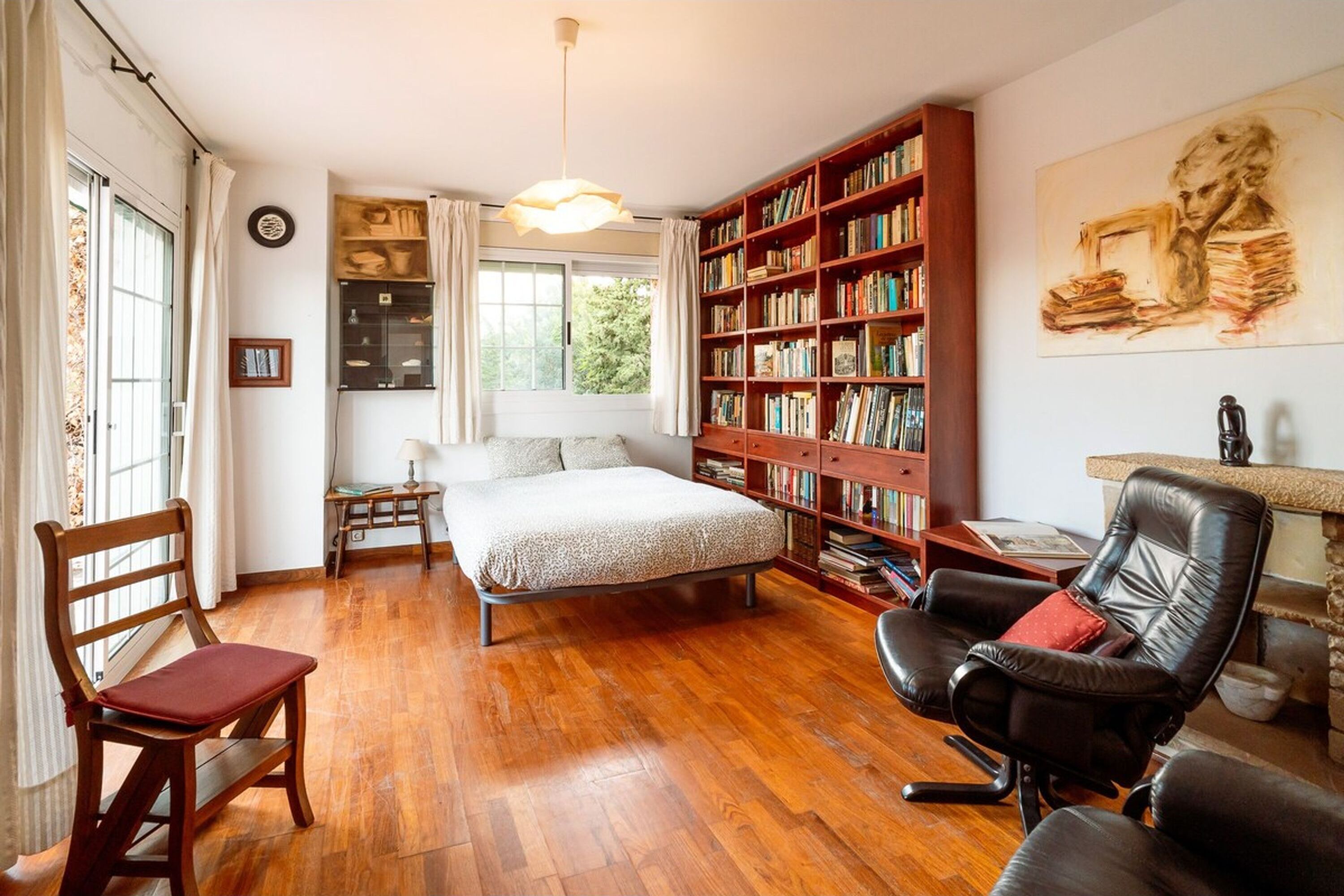 A cozy bedroom with a large wooden bookshelf, a bed, and a desk.