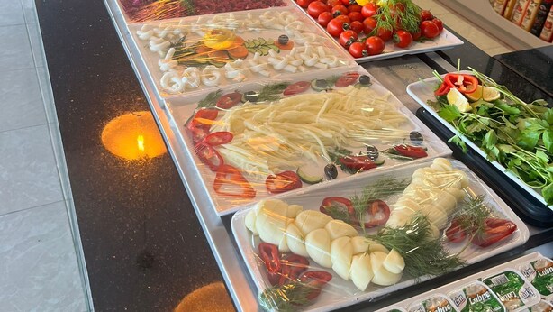 Un buffet proposant une variété d’aliments, notamment des légumes, des fromages et des produits emballés.
