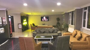 Un hall d’entrée avec un canapé, des fauteuils, un téléviseur et un comptoir de réception.