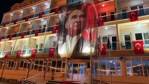 Un immeuble à plusieurs étages doté de balcons, chacun étant orné de drapeaux rouges.