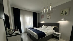 Une chambre d’hôtel moderne avec un grand lit, des tables de chevet, un bureau avec une bouilloire et un miroir.