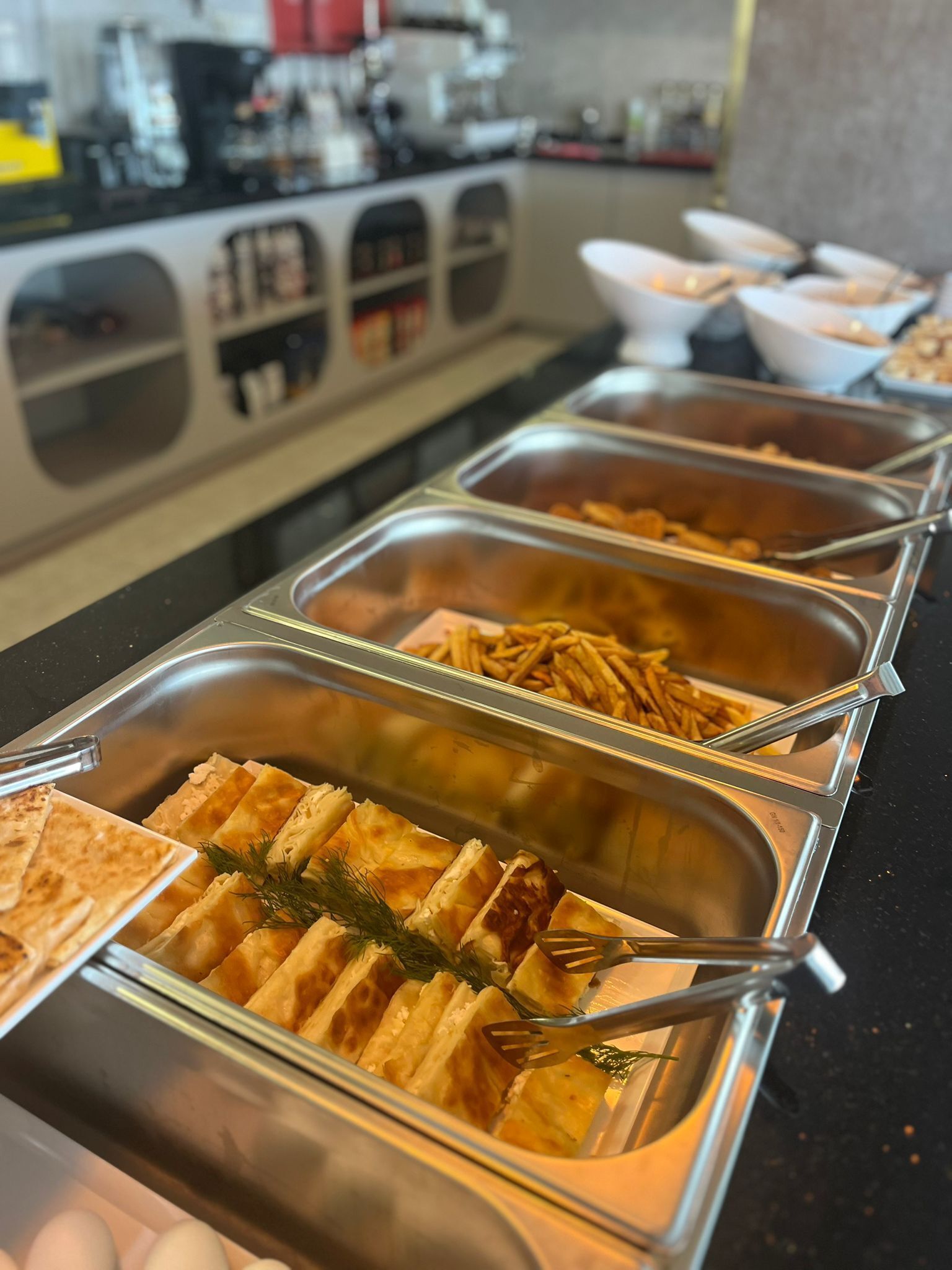 Ein Buffet mit verschiedenen Speisen, darunter Backwaren und Pommes.