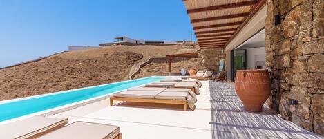 A poolside area with lounge chairs and a large terracotta pot.