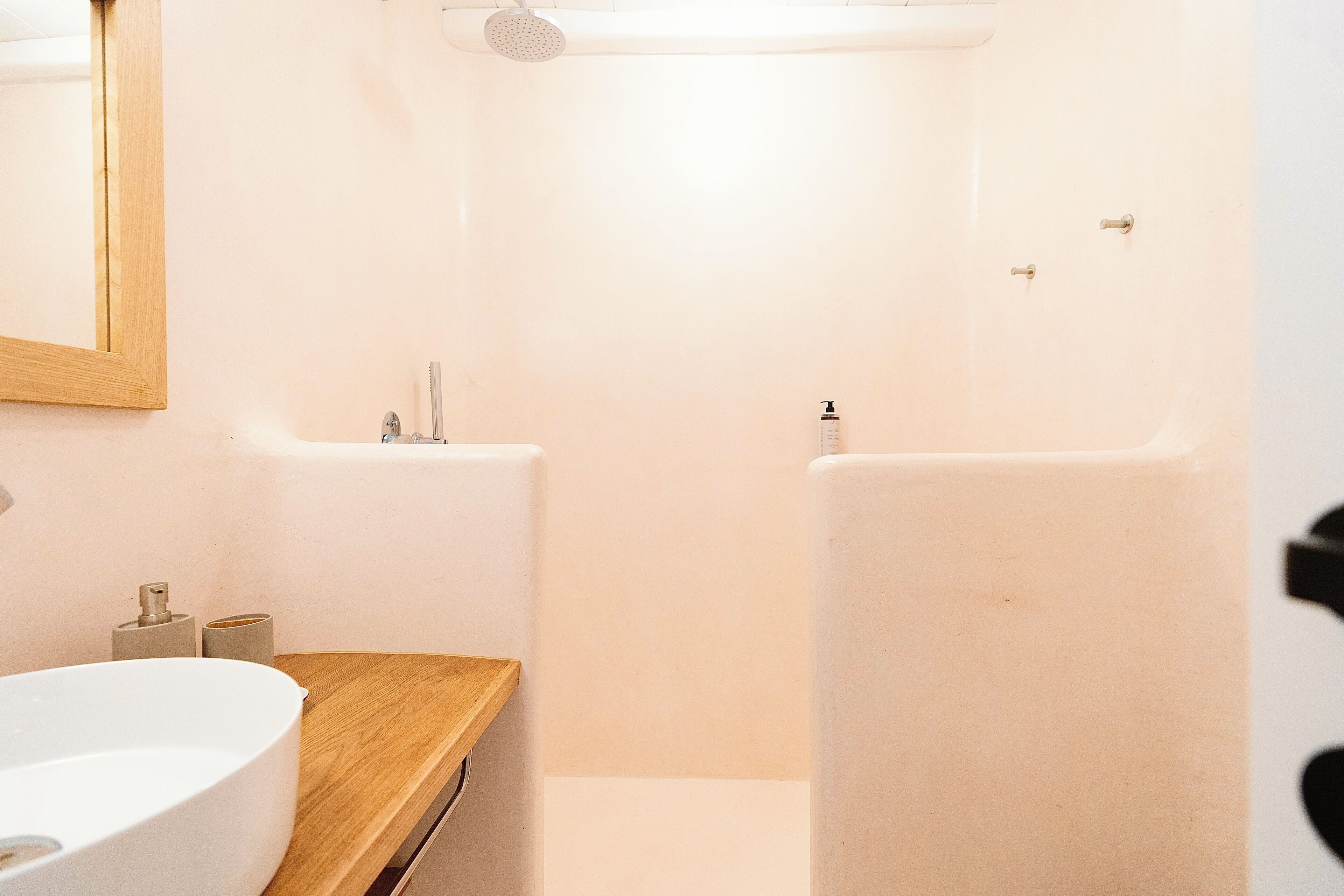 A bathroom with a wooden vanity, a white sink, and a shower area.