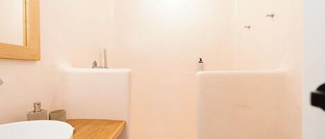 A bathroom with a wooden vanity, a white sink, and a shower area.