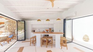A modern kitchen with a central island, bar stools, and a large window.
