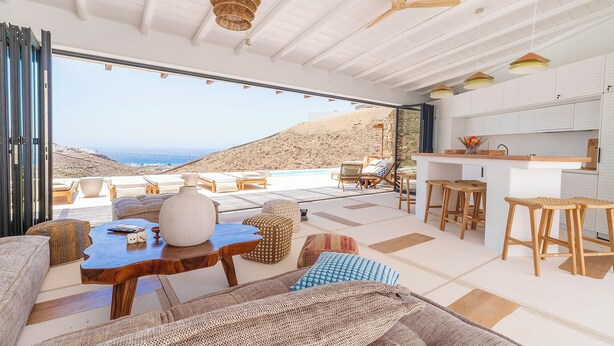 A modern interior with a large glass door leading to a terrace with a view of the sea.