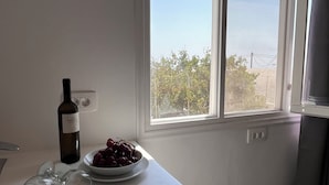 A table with a wine bottle, a bowl of grapes, and wine glasses. - High Point Apartments Fira (Santorini)