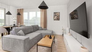 A modern living room with a sectional sofa, a wooden coffee table, and a flat-screen TV mounted on the wall.