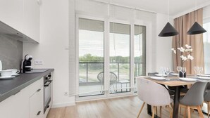 A modern kitchen with a dining area, large windows, and a view of the outdoors.