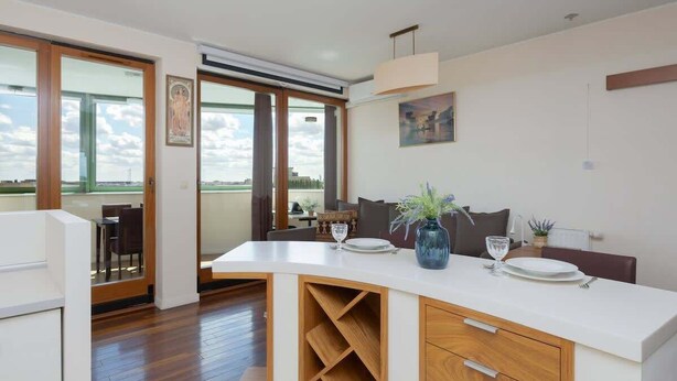 A modern kitchen with a large island, wooden cabinetry, and a view of the outdoors.