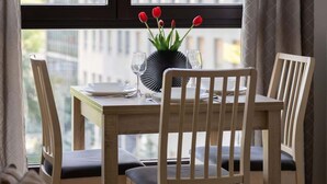 Una mesa de comedor con sillas, un florero con tulipanes rojos y vista al exterior.