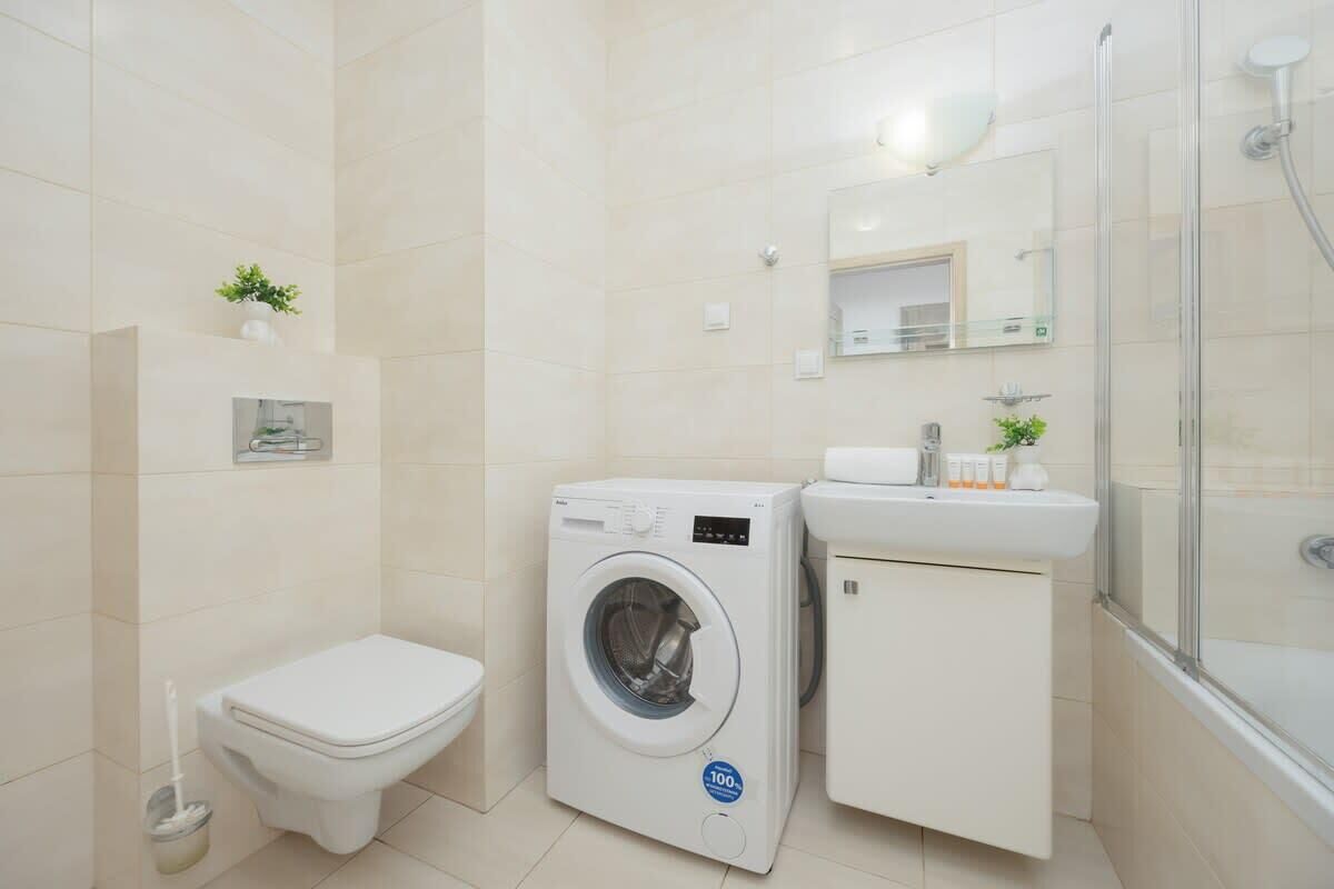 Un baño pequeño con inodoro, lavadora y zona de ducha.