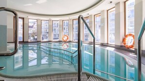 An indoor swimming pool with glass walls, metal railings, and windows with city views. - Spacious Apartment | 3 Bedrooms, Pool, Parking. (Zakopane)