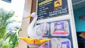 A swan sculpture on a yellow base with a sign for Hotel Natasha Regina in the background. - Hotel Natasha Regency (Bengaluru)