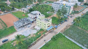 An aerial view of a residential area with multi-story buildings, a road, and surrounding greenery. - Hotel Natasha Regency (Bengaluru)
