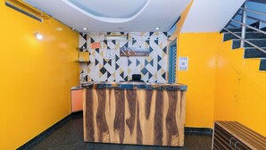 A reception desk with a sign for Hotel Natasha Regency, a clock, and a patterned wall. - Hotel Natasha Regency (Bengaluru)