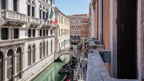 A canal with gondolas, a bridge, and buildings with flags. - Residenza San Marco (Venice)
