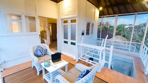 A spacious balcony with white wicker furniture, a laptop on a table, and a view of the surrounding landscape. - Noya Bed and Breakfast (Ubud)