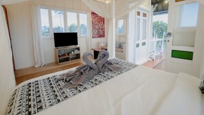 A bedroom with a bed, a TV, and a balcony. - Noya Bed and Breakfast (Ubud)