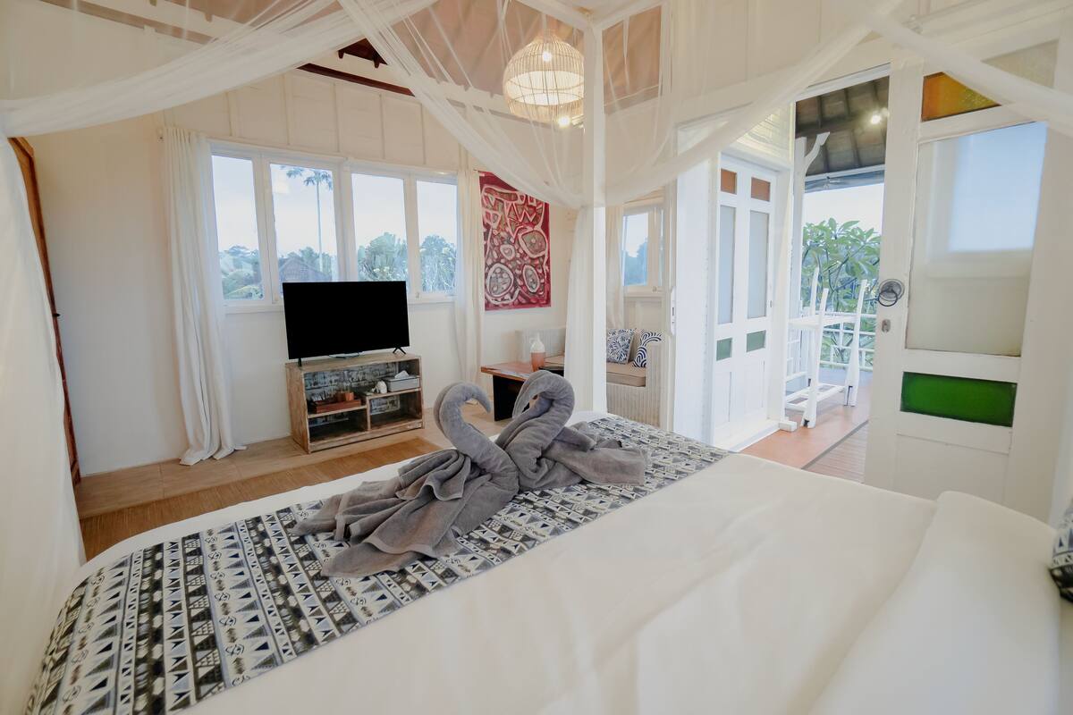 A bedroom with a bed, a TV, and a balcony.