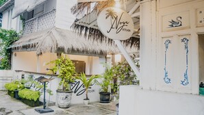A restaurant with a thatched roof, outdoor seating, and potted plants. - Noya Bed and Breakfast (Ubud)