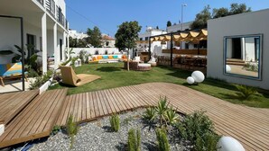 A modern outdoor patio with wooden decking, a grassy area, and outdoor seating. - Glitz Bodrum (Bodrum)
