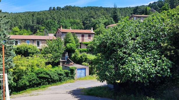 A rural village with stone houses, a gate, and lush greenery.