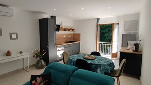 A compact living space with a kitchenette, dining area, and a balcony with a view.