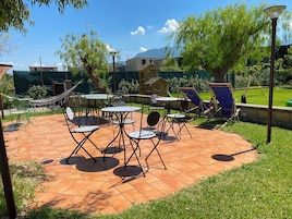 Un patio con mobiliario exterior, una hamaca y un conjunto de columpios.